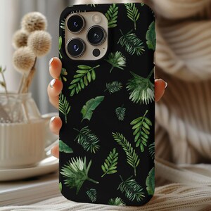 May include: Black phone case featuring a repeating pattern of green watercolor leaves. The leaves vary in size and shape, creating a tropical or botanical theme. The case has a glossy finish and is designed for a smartphone.