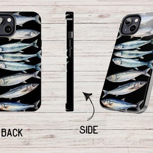 以下が含まれることがあります： 黒い背景に銀色の魚のデザインが施された黒い携帯電話ケース。ケースにはカメラの盛り上がりが付いており、側面は黒です。