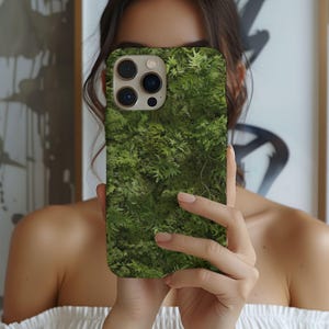 Może przedstawiać: Zielono-brązowe etui na telefon z fakturą mchu. Etui ma wycięcie na obiektyw aparatu i białą ramkę.