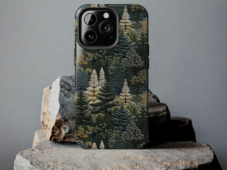 May include: A black phone case with a forest scene design. The case features a repeating pattern of green, brown, and yellow trees.