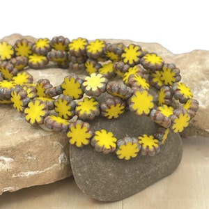 May include: A strand of yellow and brown ceramic flower beads. The beads are arranged in a circular pattern and have a glossy finish.