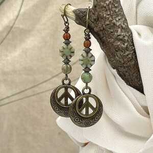 a pair of peace earrings hanging from a tree branch