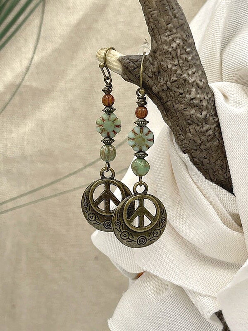 a pair of peace earrings hanging from a tree branch