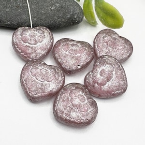 May include: Six pink heart-shaped glass beads with a silver metallic finish and a raised floral design.