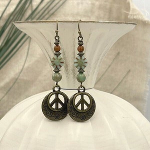 a pair of earrings with beads and a peace sign
