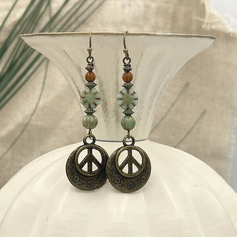 a pair of earrings with beads and a peace sign