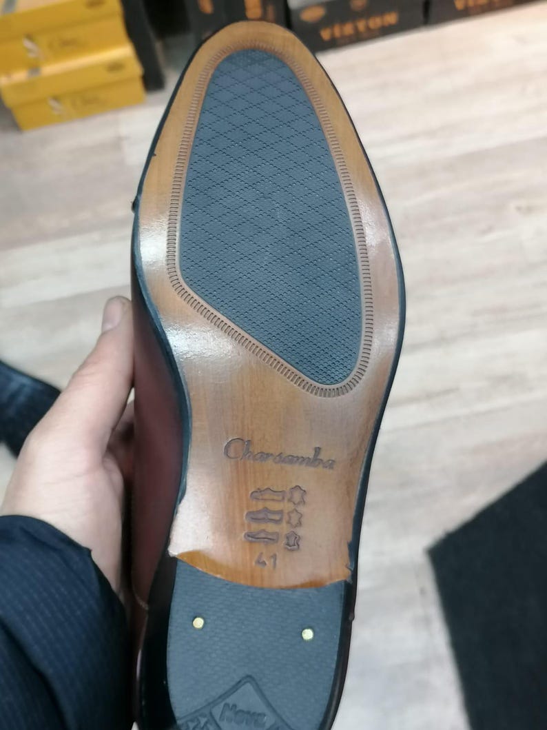 May include: Close-up of the sole of a brown leather dress shoe. The sole features a textured blue rubber insert, a wooden heel, and the brand name "Charsamba" is visible. Size 41 is stamped on the sole.