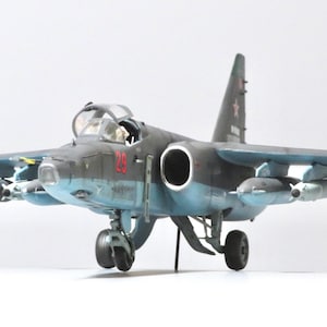 Può includere: Modello dettagliato di un aereo da combattimento militare, prevalentemente grigio e blu, con accenti rossi. Il modello presenta dettagli intricati, tra cui missili e un abitacolo. Il numero "29" è visibile sul lato. L'apertura alare è di circa 25 cm.