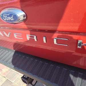 May include: A red Ford Maverick pickup truck with a chrome "Maverick" emblem on the tailgate.