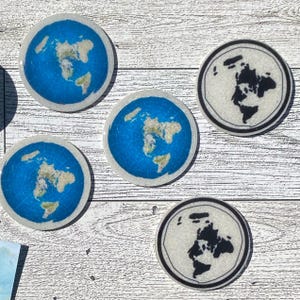 May include: A collection of round coasters featuring a flat earth map design. The coasters have a blue ocean background with continents in shades of green and tan. Some coasters have a black and white world map.