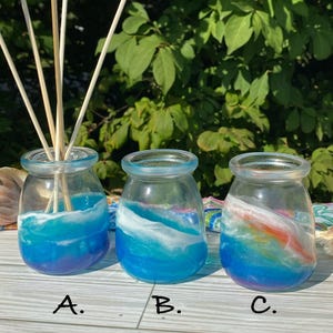 May include: Three glass jars with blue, white, and orange resin inside. The jars are labeled A, B, and C. The resin looks like ocean waves.