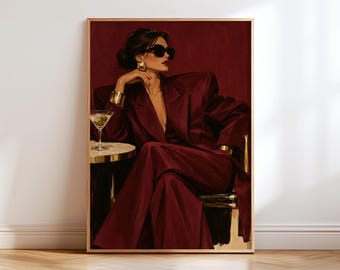 May include: A framed wall art print depicting a person in a deep burgundy oversized blazer and matching trousers, wearing black sunglasses and gold jewelry. The person sits at a small table with a martini glass containing green olives.