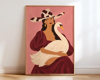 May include: A framed art print featuring a person wearing a cow-print cowboy hat and a dark red dress with puff sleeves. The person is holding a large white swan against a solid pink background. The illustration uses flat colors and bold lines.