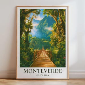 May include: A framed vertical wall art print featuring a wooden suspension bridge leading into a lush green rainforest with tall trees and distant mountains. The text MONTEVERDE COSTA RICA is printed in black capital letters at the bottom of the poster.