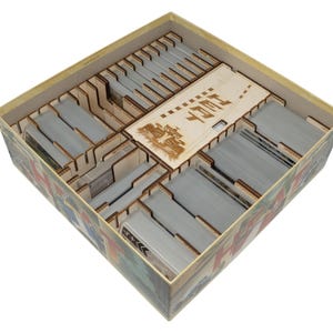 May include: A square board game box containing a light-colored wooden organizer insert with multiple compartments. The insert holds stacks of gray playing cards and features a wooden lid engraved with the word HEAT and a race car graphic.