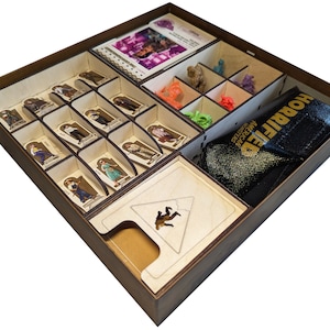 Op de afbeelding: Een houten doos met een aangepaste insert voor het organiseren van een bordspel. De insert heeft compartimenten voor miniatuurfiguren, kaarten en een tas. De doos is gelabeld "Hobbit: The American Adventure".