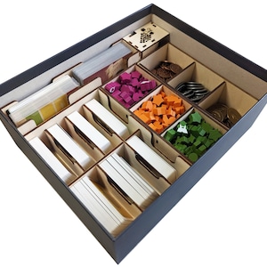 May include: A wooden game organizer with compartments for storing game pieces and cards. The organizer has compartments for coins, wooden meeples, and cards. The organizer is made of wood and has a dark gray finish.