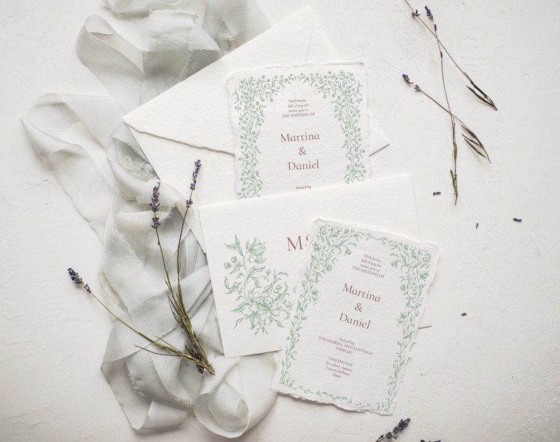 May include: Two wedding invitations with a green floral border and the text "With love, we invite you to celebrate the wedding of Martina & Daniel" printed in burgundy.