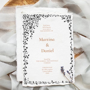 Pu&ograve; includere: Invito di nozze bianco con un bordo floreale nero decorativo. I nomi "Martina & Daniel" sono visualizzati in un carattere marrone caldo. L'invito include i dettagli dell'evento ed &egrave; impreziosito da un rametto di lavanda.