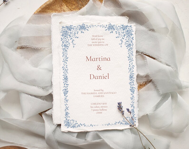 May include: Wedding invitation with a blue floral border. The invitation is for Martina & Daniel, hosted by the Haskell and Santiago families. The wedding will take place in Chileno Bay, Los Cabos, Mexico.