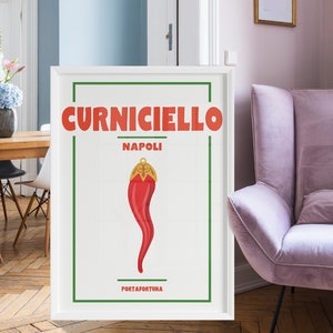 Può includere: Un poster incorniciato bianco con un'illustrazione rossa e dorata di un peperoncino. Il poster ha il testo "Curniciello Napoli Portafortuna" stampato su di esso.