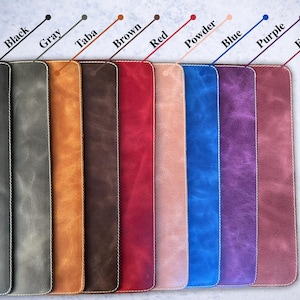 May include: Ten leather swatches in different colors, including black, gray, brown, red, powder, blue, purple, and fuchsia. The swatches are arranged horizontally and have a white stitching around the edges.