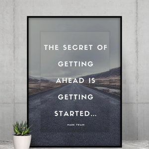 May include: Framed print featuring a road leading into the distance under a cloudy sky. The print displays the quote "THE SECRET OF GETTING AHEAD IS GETTING STARTED..." by Mark Twain in white text. A small potted succulent is in the foreground.