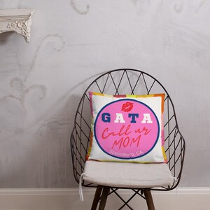 May include: Square throw pillow with a white background and a colorful design. The pillow features a pink circle with the text "GATA Call us MOM Statesboro, GA" in blue and white. A red lip graphic is at the top.
