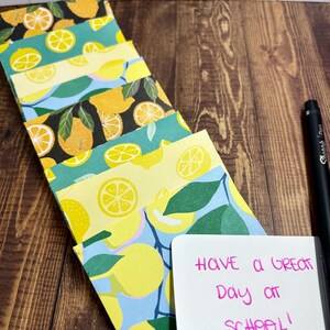 May include: A stack of colorful note cards with a lemon and leaf pattern. The top card has a handwritten message that says "Have a great day at school!"