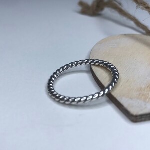 Op de afbeelding: Een zilveren ring met een gedraaid touwontwerp.