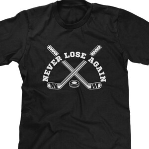 May include: Black t-shirt with a white graphic of two hockey sticks crossed with a puck in the middle. The text "Never Lose Again" is written around the sticks.