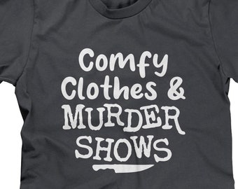 Può includere: Maglietta grigio scuro con testo bianco che recita "Comfy Clothes & Murder Shows" e una grafica di coltello bianco.