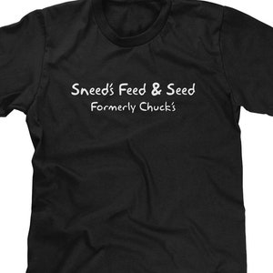 May include: Black t-shirt with white text that reads "Snead's Feed & Seed Formerly Chuck's"