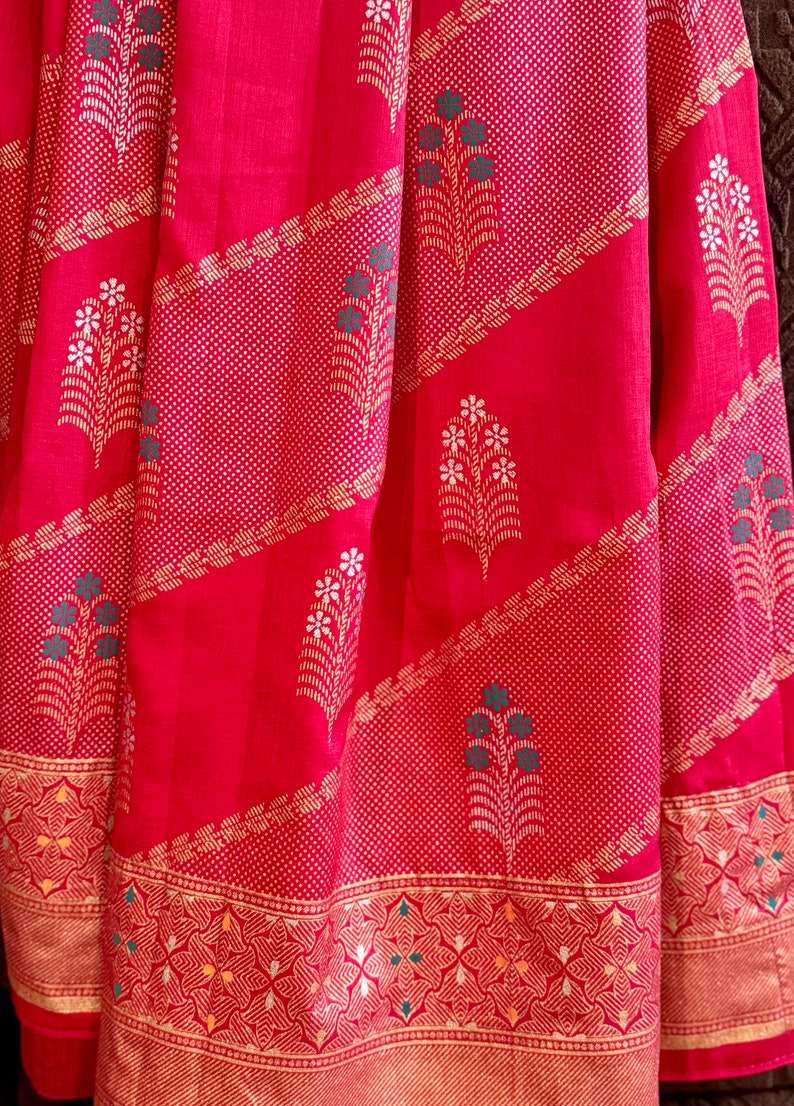 May include: Red fabric with a gold and white floral pattern. The fabric has a gold border with a geometric design.