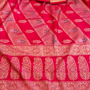 May include: Red silk saree with a gold and silver border and intricate paisley patterns. The saree has a traditional Indian design and is perfect for special occasions.