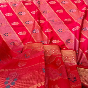 May include: Red silk saree with gold and silver thread embroidery. The saree features a paisley design and a floral pattern.
