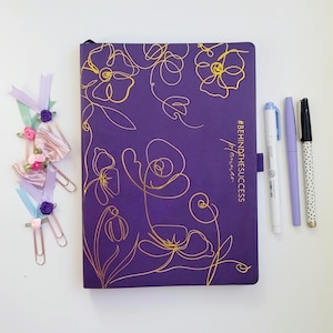 May include: Purple planner with gold floral design and the text "#BEHINDTHESUCCESS by the planner".