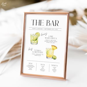 以下が含まれることがあります： THE BARと書かれたローズゴールドの額縁入りサイン。Cheryl & Graham、202X年9月25日の日付入り。ライムマルガリータとウォッカレモネードの水彩画イラストに加え、ワイン、ビール、スピリッツのカテゴリーと具体的な銘柄名が記載されています。