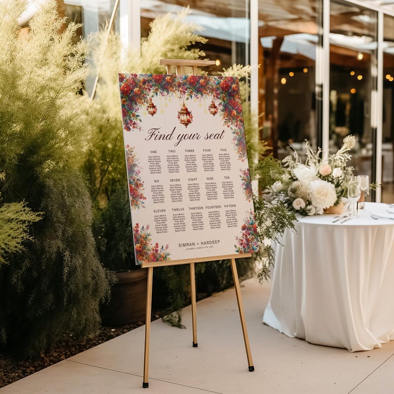 May include: A wedding seating chart on a wooden easel. The sign reads "Find your seat" and is decorated with floral arrangements and hanging lanterns. The names are listed in columns, with the couple's names and date at the bottom.
