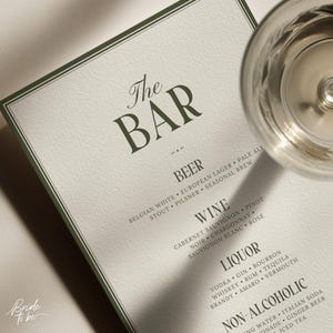 May include: A drinks menu with the title "The BAR" in a decorative font. The menu lists beer, wine, spirits, and soft drinks. A clear glass is visible in the top right corner. The words "Bride To be" are in the lower left corner.
