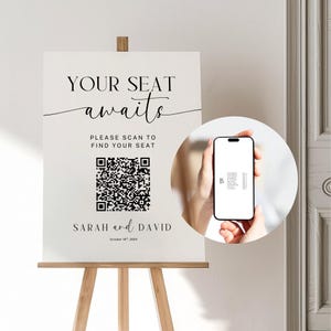 以下が含まれることがあります： 「YOUR SEAT awaits PLEASE SCAN TO FIND YOUR SEAT」という黒い文字が書かれた白い看板で、下にQRコードがあります。看板には「SARAH and DAVID」という名前と「October 16th, 202X」という日付も書かれています。手は、画面に座席表が表示されたスマートフォンを持っています。