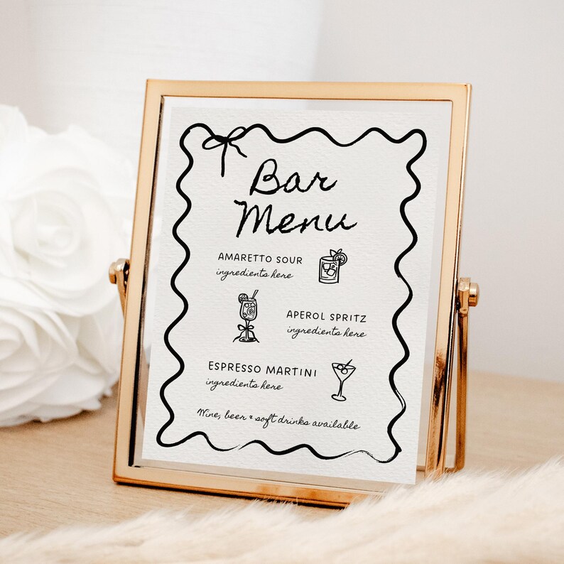May include: A gold-framed sign with a black and white bar menu. The menu lists drinks like Amaretto Sour, Aperol Spritz, and Espresso Martini. The sign says "Bar Menu" at the top.