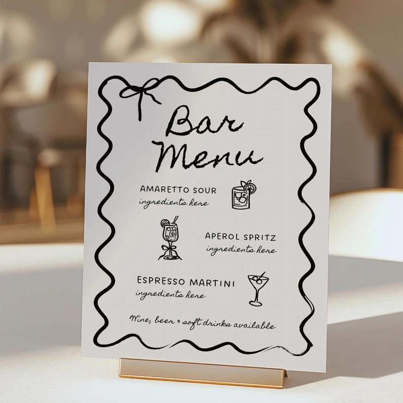 May include: A white sign with a black wavy border and the text "Bar Menu" in black cursive. The sign lists three cocktails: Amaretto Sour, Aperol Spritz, and Espresso Martini. Each cocktail is illustrated with a simple line drawing of a glass. The sign also includes the text "Wine, beer & soft drinks available."