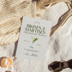 May include: A white card with green text that reads "Join is for a Bikini's & Martini's Bachelorette Weekend" with a green illustration of a martini glass with olives. The card also includes the text "April 6-8, 2025 Orlando, FL" and "Join is for a bachelorette weekend to celebrate the bride to be Ava M&uuml;ller."