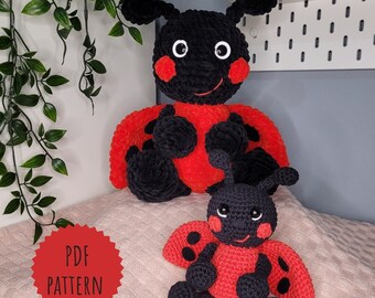 May include: Two crocheted ladybug toys, one large and one small, with black and red yarn. The larger ladybug has a smiling face and black spots. The smaller ladybug has a similar design. The toys are sitting on a pink and white fuzzy surface. The text "PDF PATTERN" is on a red starburst.
