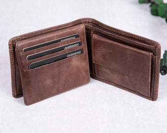 May include: A brown leather wallet with multiple card slots and a billfold. The wallet is open and has three credit cards inside.