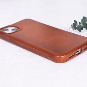 May include: A brown leather phone case for an iPhone.