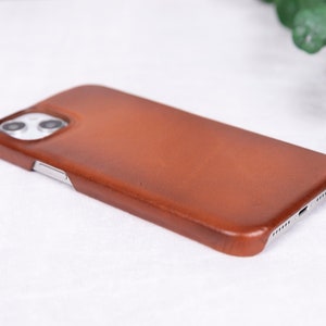 May include: A brown leather phone case for an iPhone.