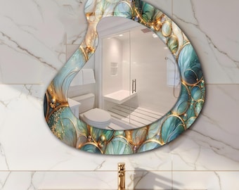 May include: An abstract-shaped wall mirror with a decorative border. The border features a teal, gold, and white design with a swirling pattern. The mirror reflects a bathroom with a white toilet, shower, and marble walls.
