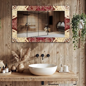 May include: A rectangular mirror with a decorative border featuring a repeating pattern in burgundy, cream, and gold tones. The mirror is mounted on a wooden wall above a white sink, with a view of a bathroom.